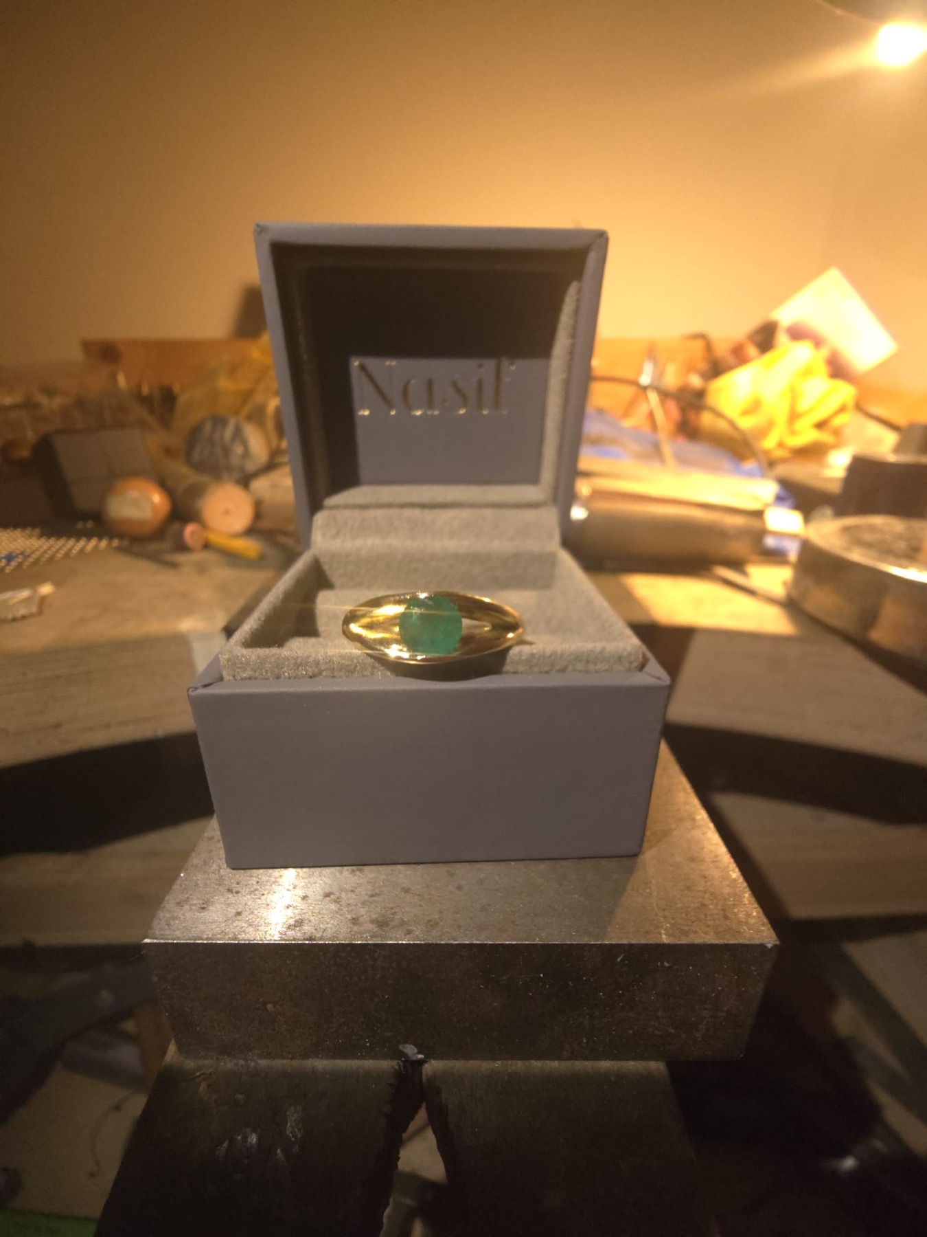 Finished emerald gold ring presented in its Nasif box on the workbench