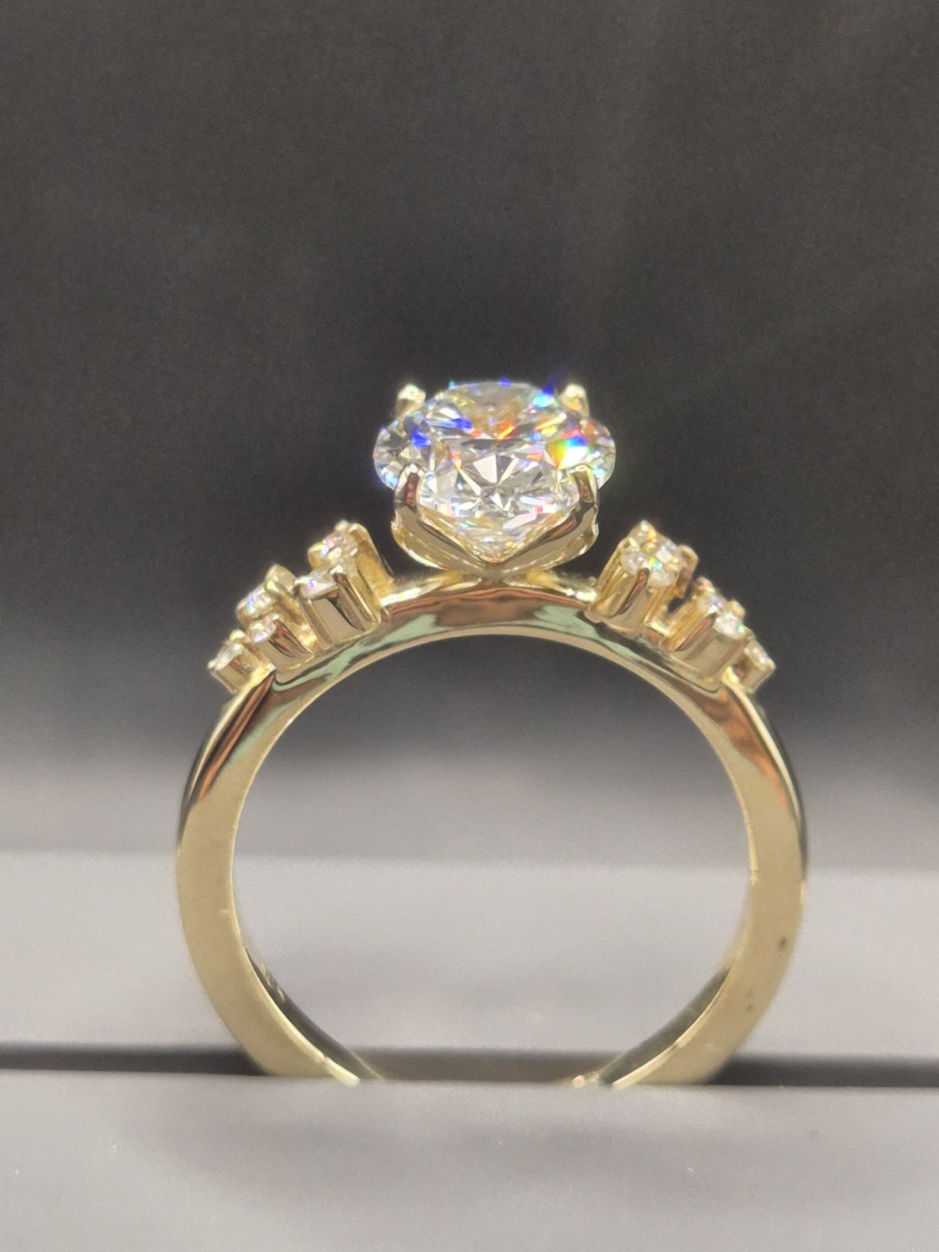 Round brilliant diamond solitaire in yellow gold with accent stones on the shoulders